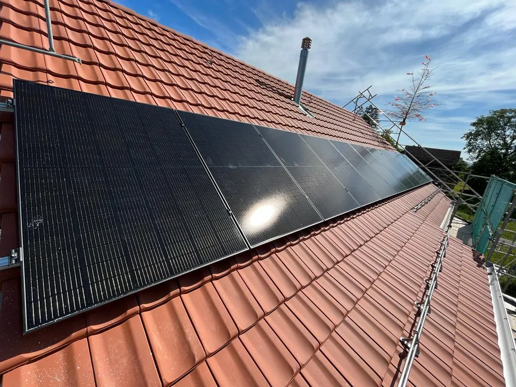 Schwarze Solarmodule auf einem roten Ziegeldach